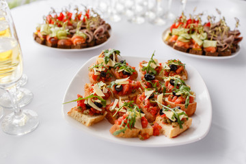 Plate with Italian appetizers. Bruschetta with a cherry tomatoes and shrimps. Parmesan cheese, olives, sun-dried tomatoes and walnuts.