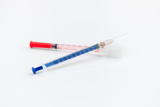 Closeup shot of two disposable insulin syringes crossed isolated on white background, medicine and treatment concept