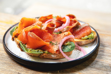 Delicious toasts with smoked salmon, avocado and basil leaves