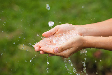 Fototapeta premium Wet female hands and clear water splashes