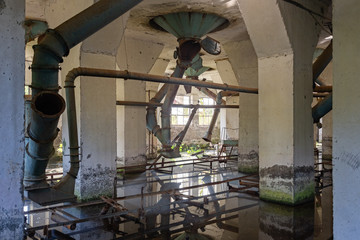 Flooded abandoned ruined flour mill factory. Old rusty pipes in dirty water