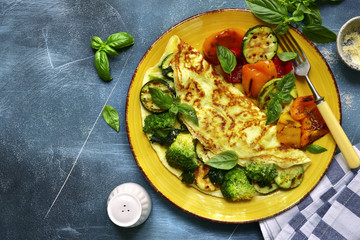 Omelette stuffed with green vegetables (broccoli, zucchini, spinach) garnished with grilled bell pepeer.Top view with copy space.