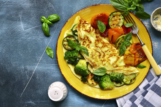 Omelette stuffed with green vegetables (broccoli, zucchini, spinach) garnished with grilled bell pepeer.Top view with copy space.
