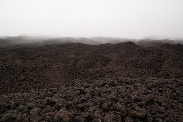Etna vulcano surrealistic landscape mountain clouds fog lava stone 