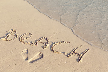 Handwritting inscription word BEACH on sand