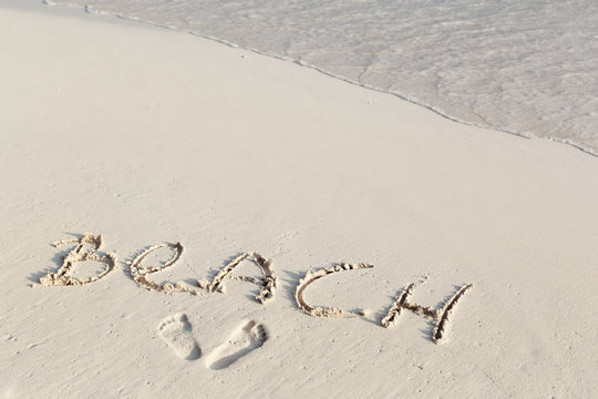 Handwritting inscription word BEACH on sand