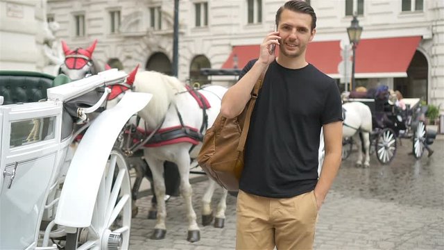 Tourist man enjoying a stroll through Vienna and looking at the beautiful horses in the carriage