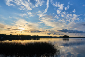 Obraz premium Sunset on the lake with cloudy sky on a background.