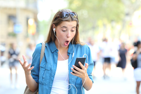 Surprised woman listening to music watching online content