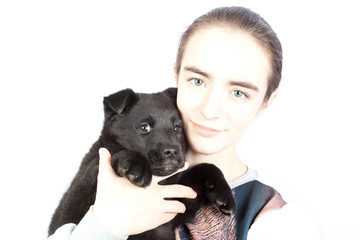 A happy teenage girl holding a German shepherd puppy in her arms