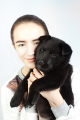 A happy teenage girl holding a German shepherd puppy in her arms