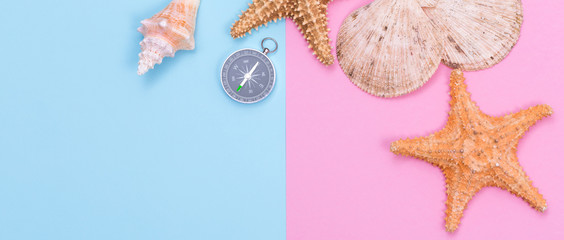 Starfish, seashell and compass on pastel colored paper texture