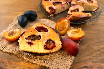Delicious and beautiful dessert - baked plum cake and fresh ripe plums purple and blue, wooden background.