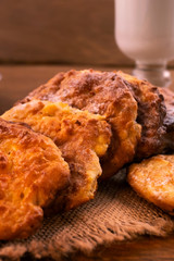 Round thin cookies with golden  crust, glass of milk, wooden background, vertical frame.