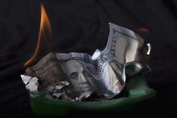 Burning dollar bill as a symbol of inflation and the financial global crisis