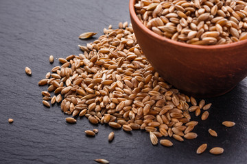 spelt seeds on a dark stone background