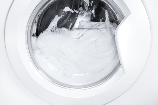 Process of cleaning white cloth in washing machine, stainless drum inside with wet towels,