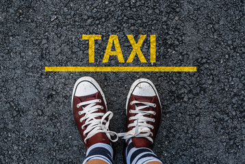 man legs in sneakers standing next to line and word TAXI
