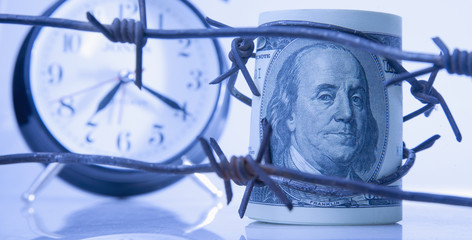 Economic warfare, sanctions and embargo busting concept. US Dollar money bill wrapped in barbed wire.