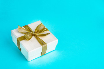 Gift or present box decorated with golden ribbon on blue background. Top view, copy space. Birthday, Mothers day, Wedding, Valentine Day concept.