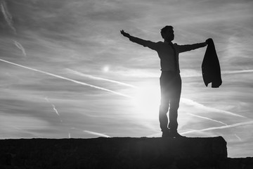 Businessman in a suit backlit by a sunburst at sunrise