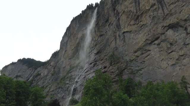 View waterfall Staubbachfall in mountains, valley of waterfalls in city Lauterbrunnen, Switzerland, Europe. Summer landscape, sunshine weather, blue sky and sunny day