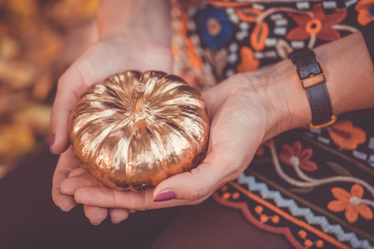 Golden pumpkin as decoration in the hands