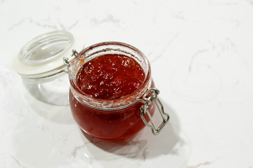 homemade strawberry jam in jar on white table