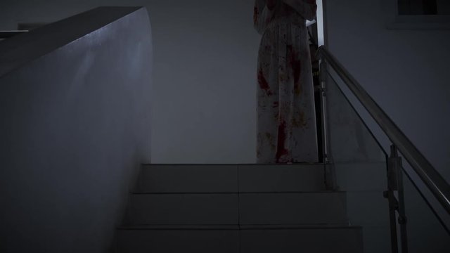 Scary ghost girl standing on the stairs at dark night in home. Halloween concept. Shot in 4k resolution
