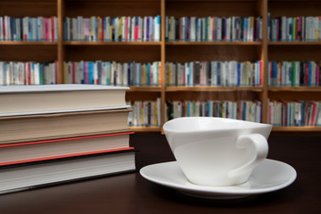 books stacked on the desk with a cup of coffee.