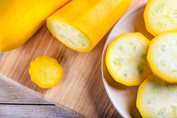 Sliced yellow zucchini on a wooden cutting board on kitchen table. Food concept. Top view.
