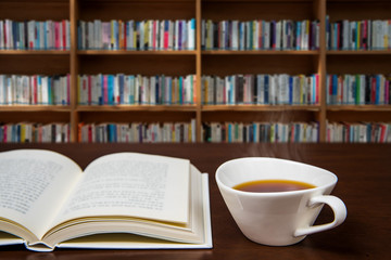 a book open on the desk with a cup of coffee.