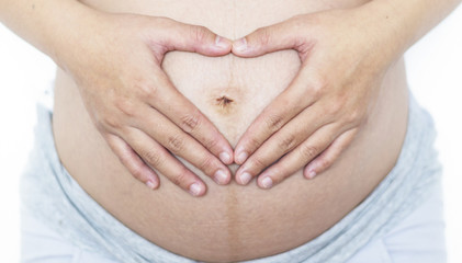Against the concept of abortion:Close up of woman's hands made heart on belly isolated on white background.health care concept