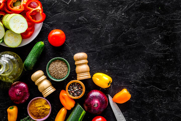 Healthy food concept. Ingredients for vegetable stew. Squash, bell pepper, tomato, spices, oil on black background top view copy space
