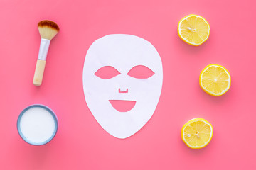 Face spa products. Facial mask, cream, brush near lemon slices on pink background top view