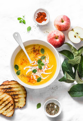 Roasted pumpkin and apples vegetarian soup on light background, top view. Flat lay. Healthy vegetarian food concept