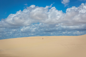 Fototapeta na wymiar Lonely man walking through a vast and empty white sand dune in northern Brazil