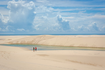 Young couple heading to a natural swimming pool through the sandy dunes in Brazil