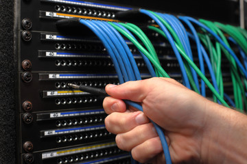 Hand inserting patch cabel into broadcast audio patch panel