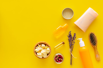 Professional shampoo, balm, conditioner based on jojoba, argan or coconut oil. Bottles and oil on yellow background top view copy space