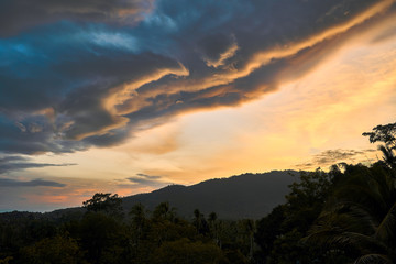Dramatic clouds against the backdrop of mountains at sunset on a tropical island. 4k time lapse