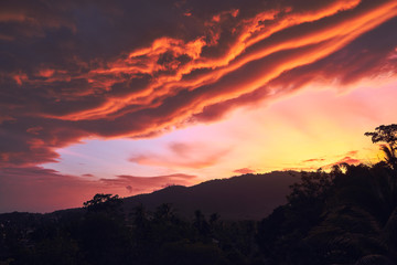 Dramatic clouds against the backdrop of mountains at sunset on a tropical island. 4k time lapse
