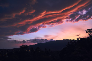 Dramatic clouds against the backdrop of mountains at sunset on a tropical island.
