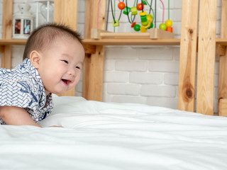 Asian Baby laughing in bedroom.