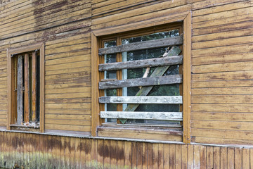 wall of old rundown wooden building with boarded up windows