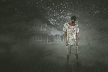 Scary male ghost stands near an abandoned house