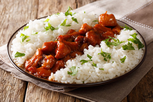 Menu in rustic style: Bourbon chicken in a sauce with whiskey, served with rice on a plate. horizontal