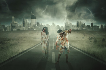 Two creepy zombies walking on the asphalt road