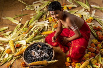 Boy in a red costume roasts carcoal on coals
