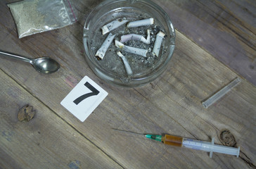 Cigarette butts in an ashtray for DNA analysis. Syringe, spoon and heroin